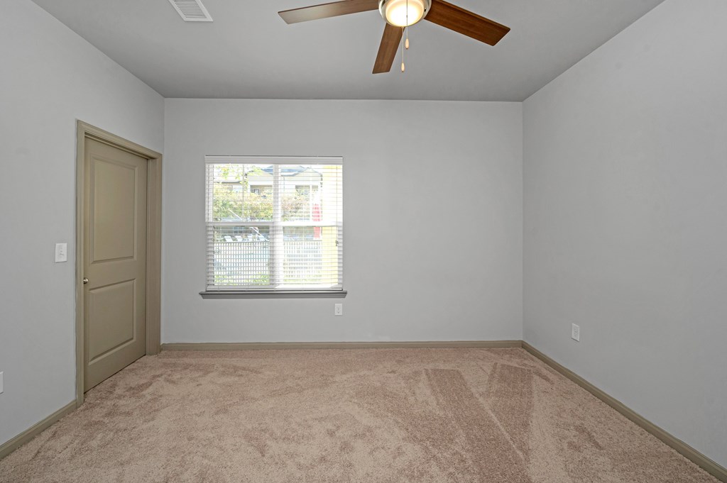 A room with a ceiling fan and a window with blinds.